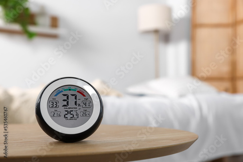 Digital hygrometer with thermometer on wooden table indoors. Space for text