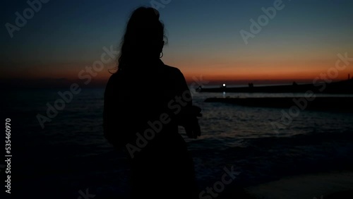The girl is having fun and dancing on the beach at sunset. Youthful joy and happiness in professional dance