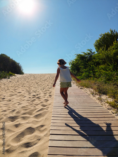 Fototapeta Naklejka Na Ścianę i Meble -  girl walking towards the beach a sunset in summer