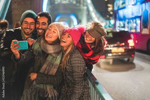 Young friends having fun doing selfie outdoor with London Tower Bridge in background - Focus on center girl face