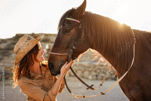 Young farmer woman having fun with her horse at farm ranch - Main focus on horse eye