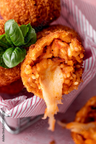 close up of the traditional Italian snack, suppli, fried rice balls with mozzarella cheese dripping, breaded and deep fried  photo