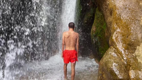 Young man walking under a waterfall photo