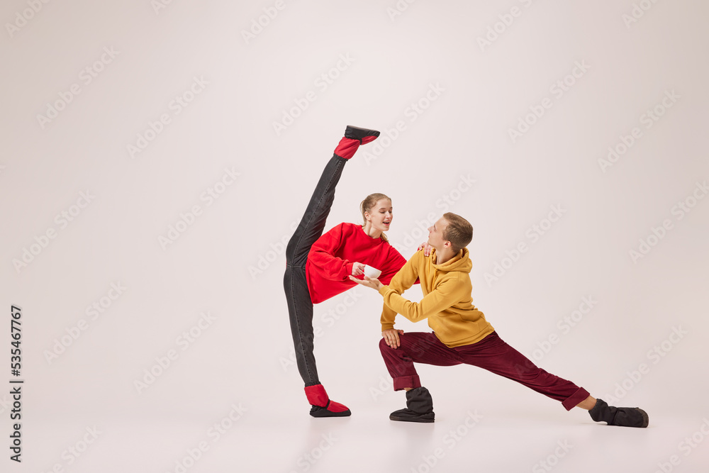 Young and graceful couple of ballet dancers in warm winter clothes dancing on grey background. Christmas, New year, holidays, party concept Young and graceful couple of ballet dancers in warm winter clothes dancing on grey background. Christmas, New year, holidays, party concept