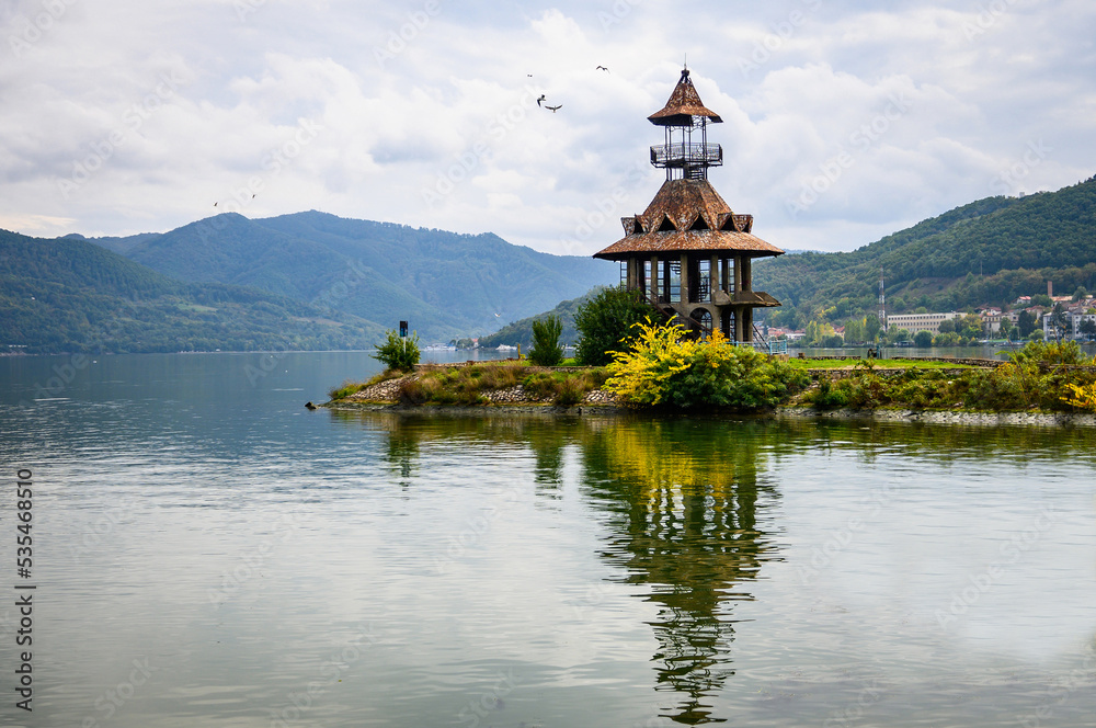 Fototapeta premium Danubian landscape. Old lighthouse, building on the bank of the Danube. Autumn on the Danube. Reflections in the water.