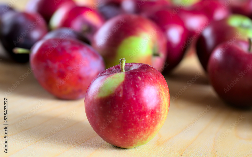 Concept for an simple autumn background. Close-up of fresh, organic fruit (apples, plums) on a wooden table. Shallow depth of field, copy space. Concept for an simple autumn background. Close-up of fresh, organic fruit (apples, plums) on a wooden table. Shallow depth of field, copy space.