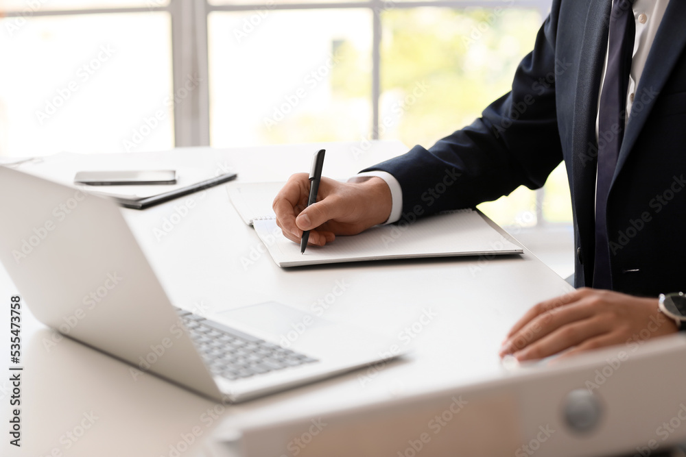 Young bank manager working with laptop at table in office