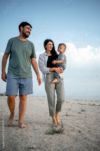 Happy family in the descent. Mom, dad and baby walk along the seashore. © Anastasia Amraeva