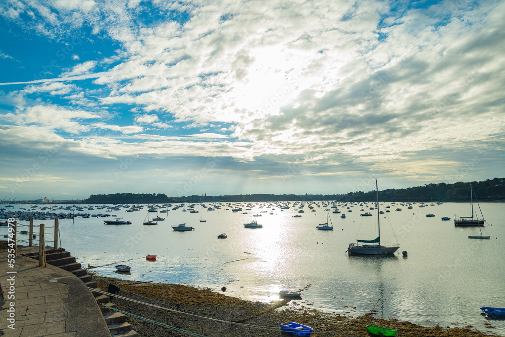 The marina of Dinard, Brittany, France, with many vessels moored. Sun and dramatic sky on the background.