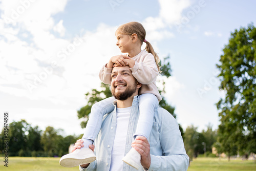 Happy father playing and carrying his daughter on shoulders.