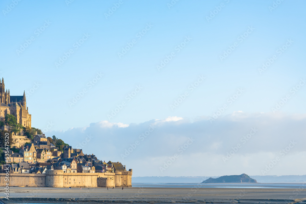 Detail of the famous Mont Saint Michel, Normandy, France. The walls with the citadel and the cathedral on the left. Blue sky on the background. With copy-space.