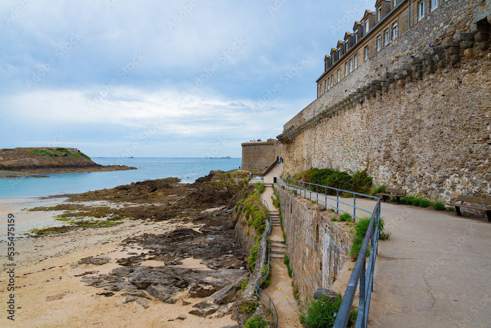 The walls and strongholds of the medieval historical centre of Saint Malo, Brittany, France. The famous rocky coastline on the left. Overcast rainy sky on the background.