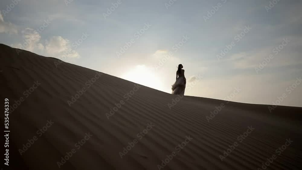 A girl in a shiny dress stands barefoot on the sand A girl in a shiny dress stands barefoot on the sand