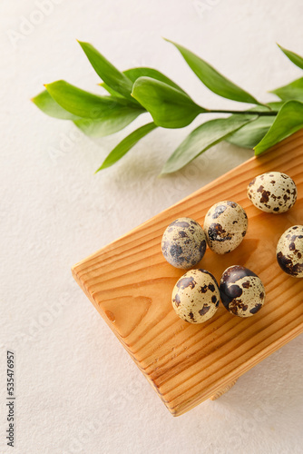 Wooden board with fresh quail eggs on light background, closeup