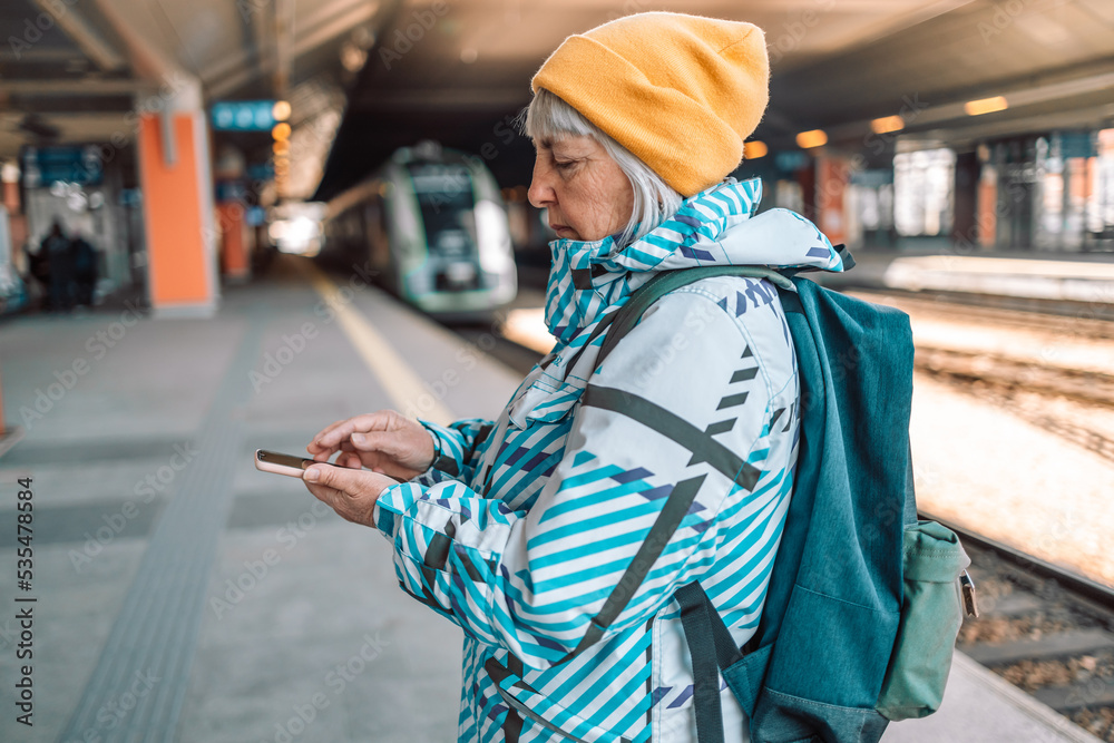 Woman holding mobile phone on sun flare platform station. Close up technology smartphone online connect. Lady travel train using gadget cellphone. Digital wifi internet lifestyle mockup. 