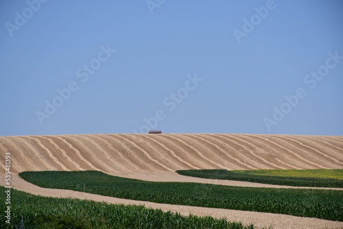Agricultural fields on beautiful hills across blue sky 