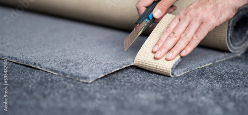 Obraz na plátně Handyman cutting a new carpet with a carpet cutter..