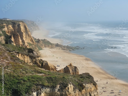 Aerial hazy view of green rocky cliffs in Praia de Vale Furado Beach in Pataias, Portugal photo