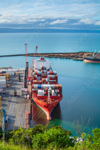 Aerial view over bright red container ship unloading at port in Napier, Hawkes Bay, New Zealand