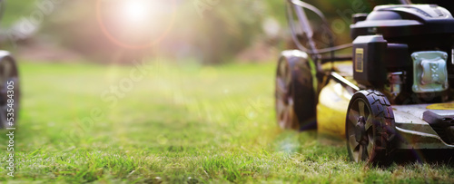 Lawn mower cut grass. Garden work. Electric Rotary lawn mower machine. Panorama, banner photo