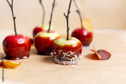 red apples in caramel, sprinkled with nuts, on a light plywood background