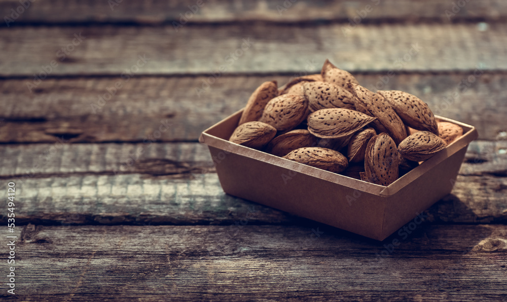 Almonds in shell on wooden background