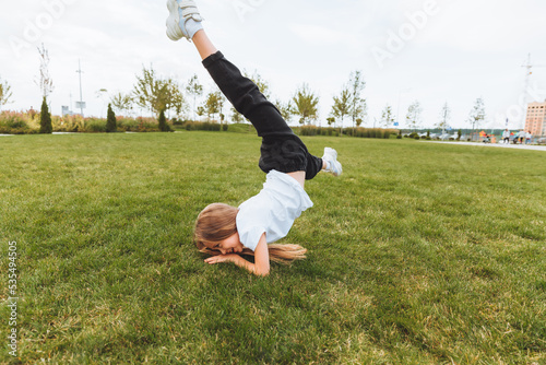 A little girl does gymnastics on the grass. a child does gymnastics in the fresh air in the park.