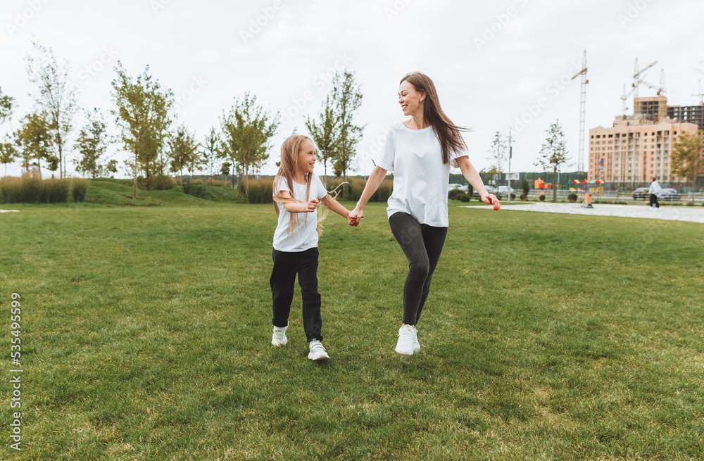 Mother and daughter play and run around the park on a beautiful day. the family is having fun in the park on the grass. morning jog.