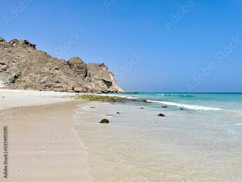 Rocky sea-cliff at Fazayah Beach under blue sky in Salalah, Oman photo