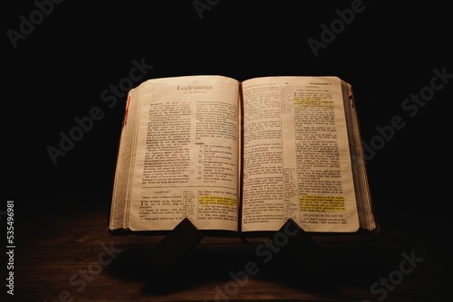 Closeup shot of a historic old Bible open on the Ecclesiastes pages on display in a dark room photo
