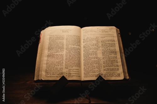 Closeup shot of a historic old Bible open on the Isaiah pages on display in a dark room