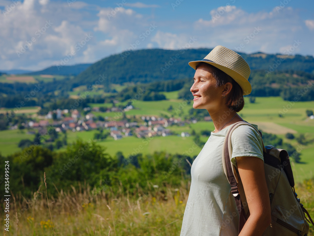 Fototapeta premium travel to summer Europe young asian woman. observation point above the village of Roggenburg, Switzerland. hike in summer forest, having a break