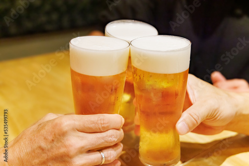 飲食店でジョッキの生ビールを乾杯する人たち