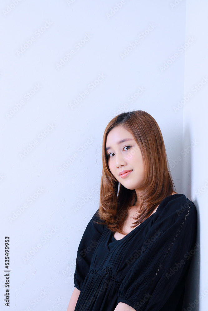 黒色のワンピースを着て壁にもたれる女性 黒色のワンピースを着て壁にもたれる女性