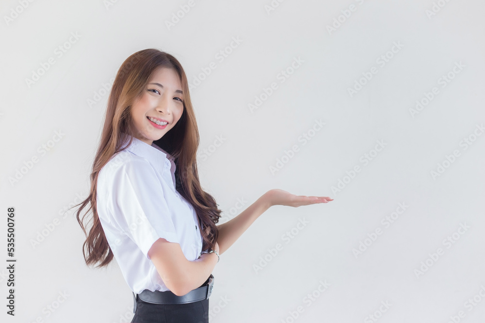 Portrait of an adult Thai student in university student uniform. Asian beautiful girl standing to present something confidently on white background.