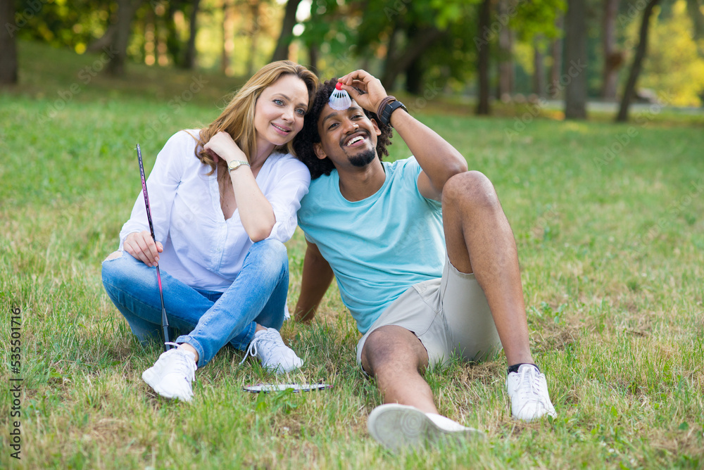 Young mixed race couple playing badminton on a summer meadow	