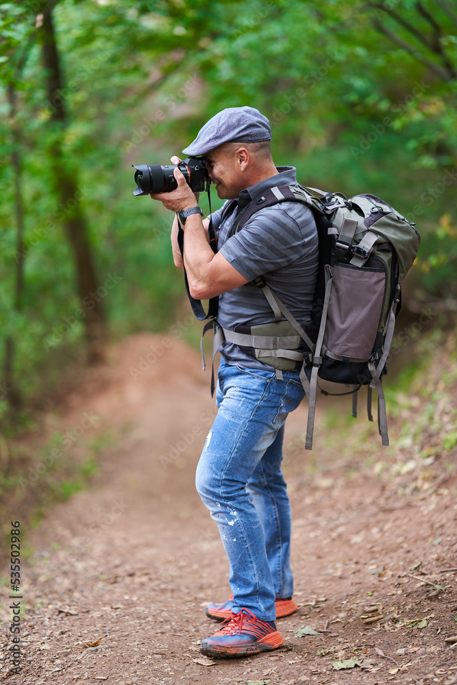 Nature and travel photographer with backpack hiking in the forest