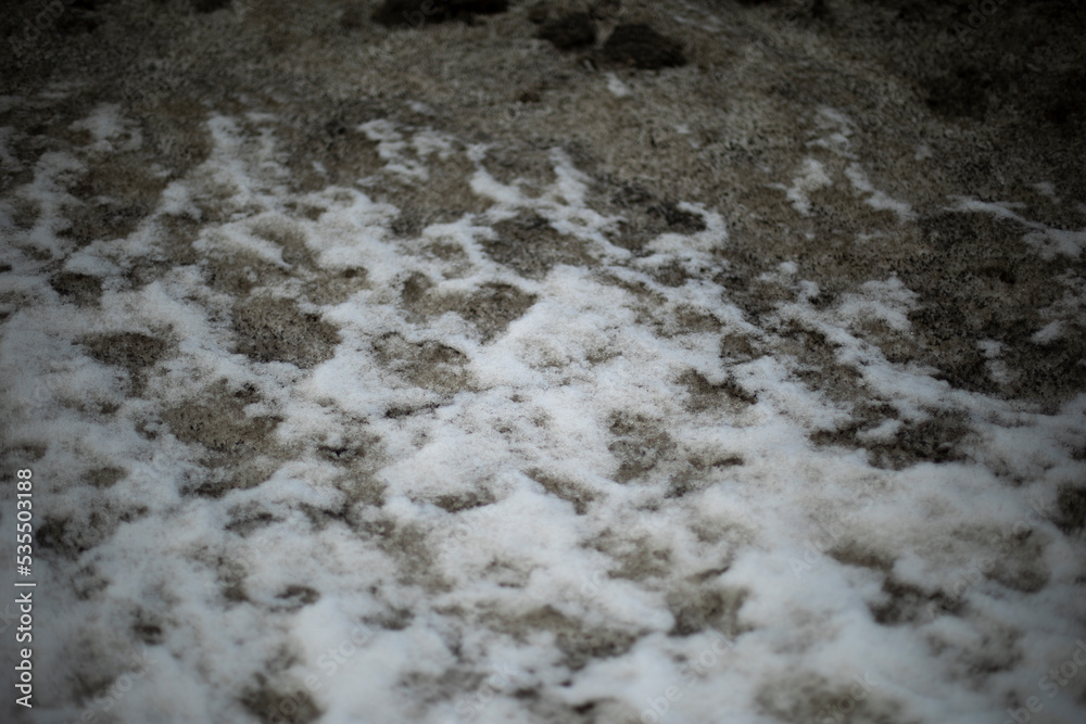 Obraz premium Dirty snow by road. Side of road in winter. Blocks of ice are black.