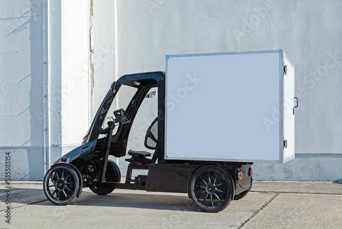 A modern electric delivery 4-wheel Quadracycle bike with a blank white cargo box with copy space for advertising.  photo