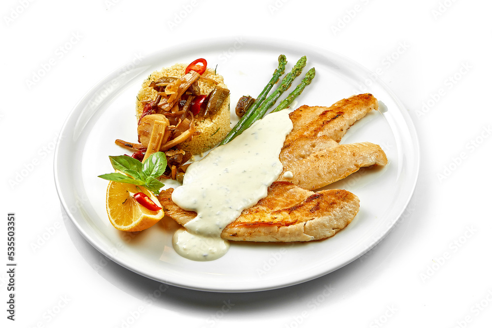 Fried fish fillet with white sauce and couscous. Close-up, selective focus