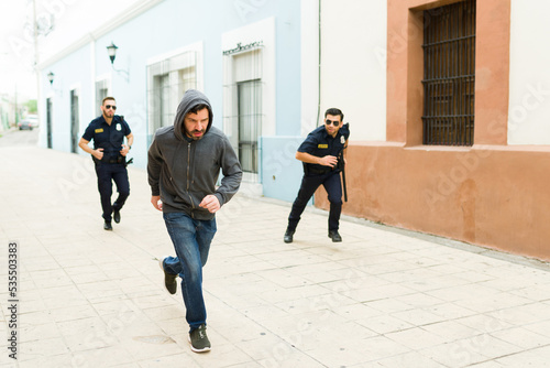 Fotografie Upset cops running after a criminal to arrest him