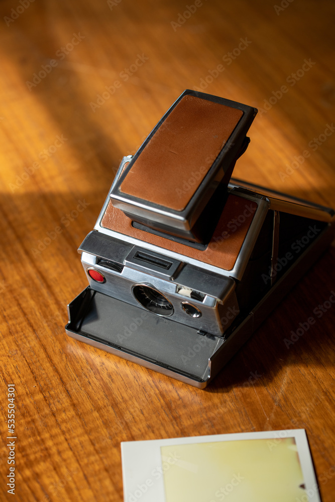 Retro instant camera on a midcentury wooden desk. Polaroid. Retro instant camera on a midcentury wooden desk. Polaroid.
