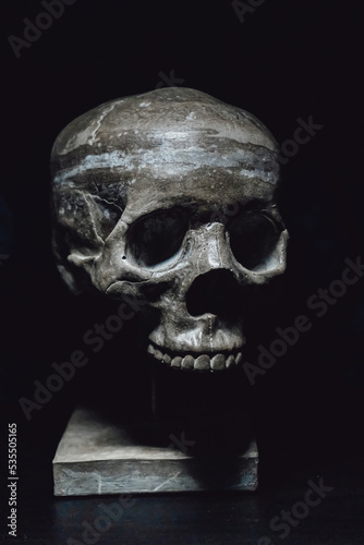 Human skull made of concrete on a stand. Interior decor.