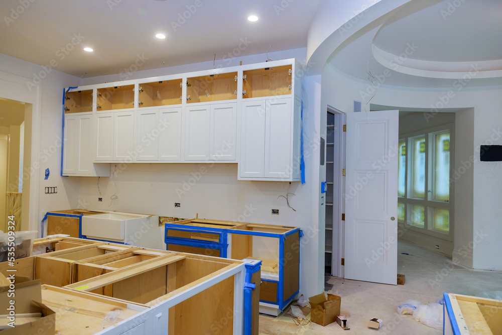 In anewly constructed house, the installation of white cabinets in kitchen was completed - obrazy, fototapety, plakaty 