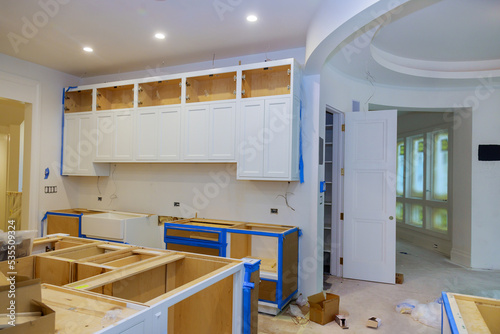 Bild auf Leinwand In anewly constructed house, the installation of white cabinets in kitchen was c