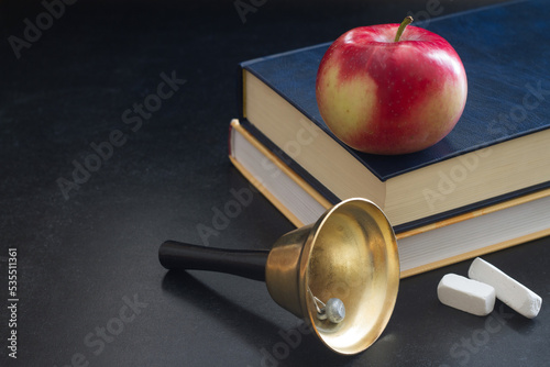 Obraz na płótnie Bell, books and apple on blackboard, back to school concept