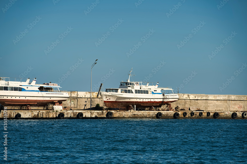 Seascape with a pier in Yalta and old boats in the parking lot.