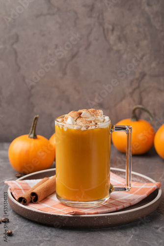 Autumn pumpkin spice latte with cream in mug and mini pumpkins on dark table. Traditional Coffee Drink for Autumn Holidays. Harvest Festival, Happy Thanksgiving. Fall time. Vertical orientation.