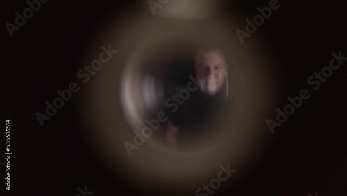 A male thief and swindler looks through the peephole from the back. The concept of theft and theft of apartments, apartment burglary. photo