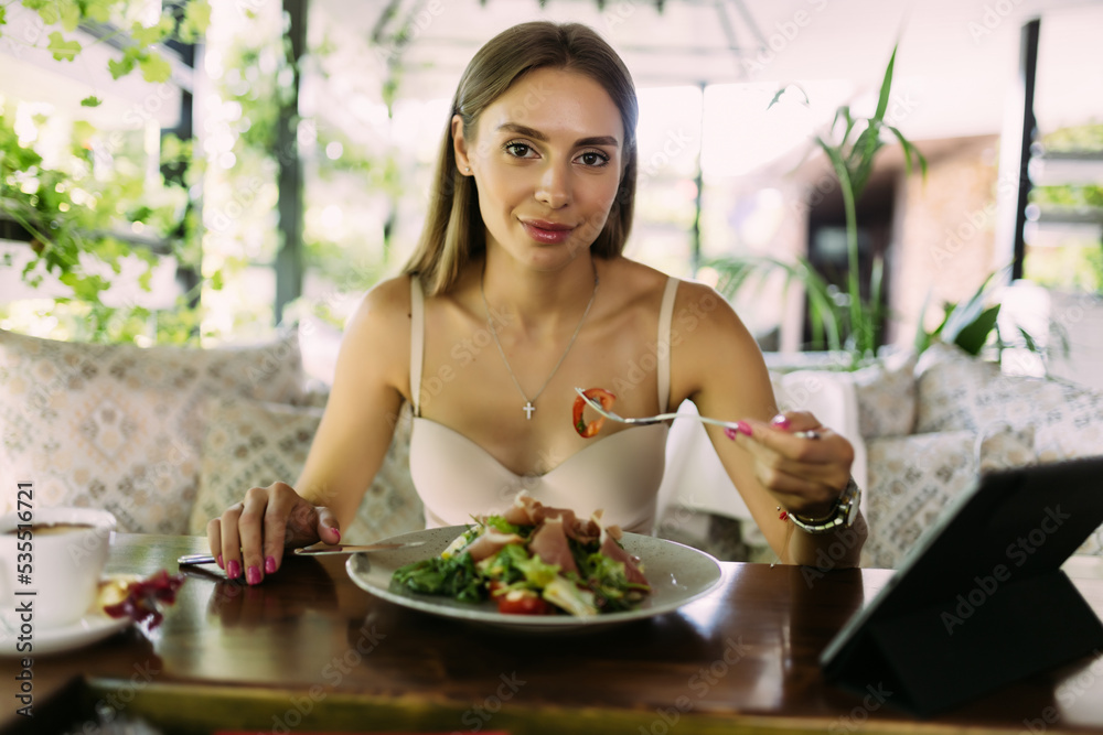 Beautiful woman using digital tablet with salad at cafe